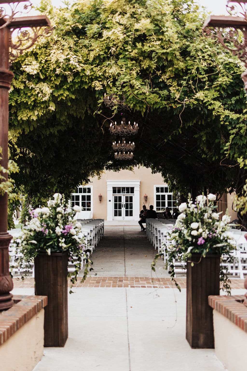 Real wedding ceremony aisle under the wisteria-covered pergola at Hotel Andaluz, Albuquerque